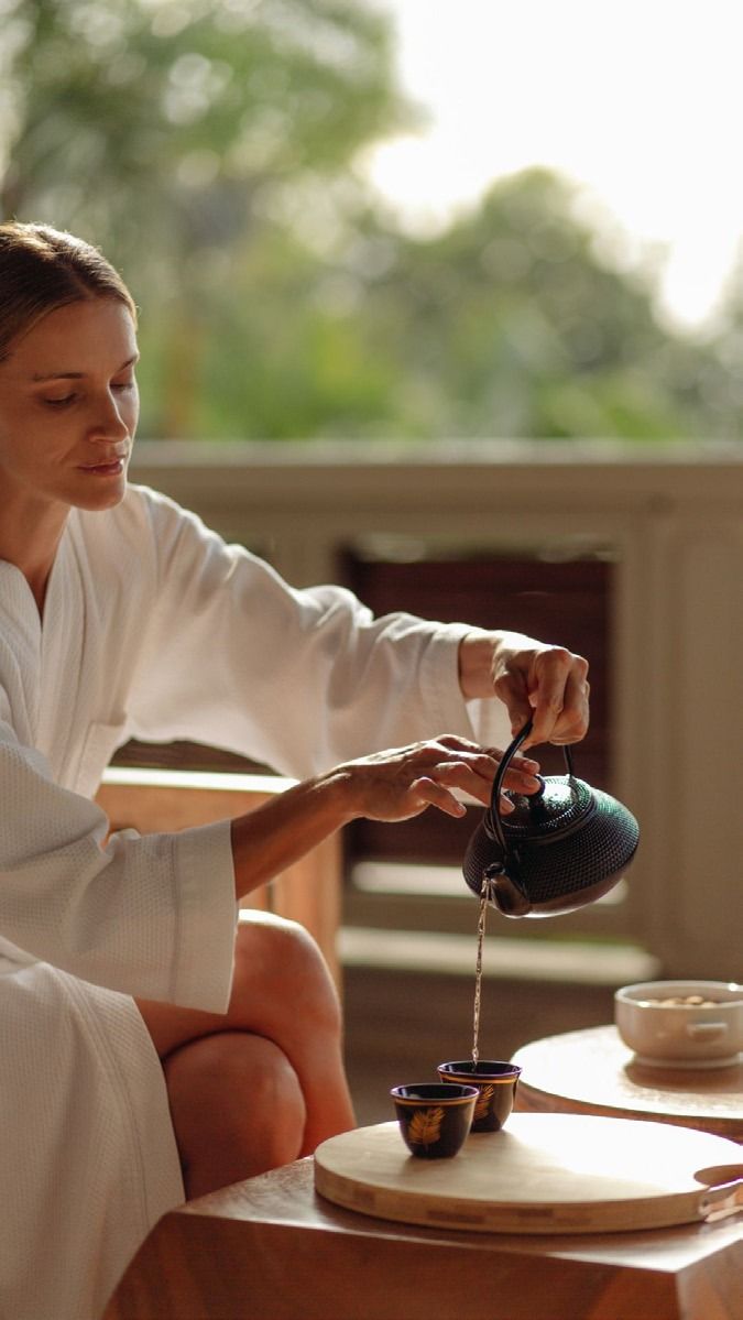 A woman taking a quiet moment to pour tea outdoors